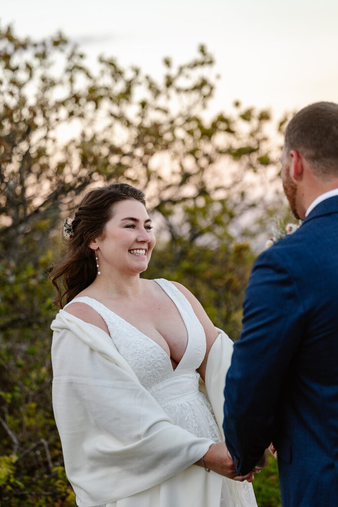 A bridge looks at her groom smiling during the vows on their wedding day