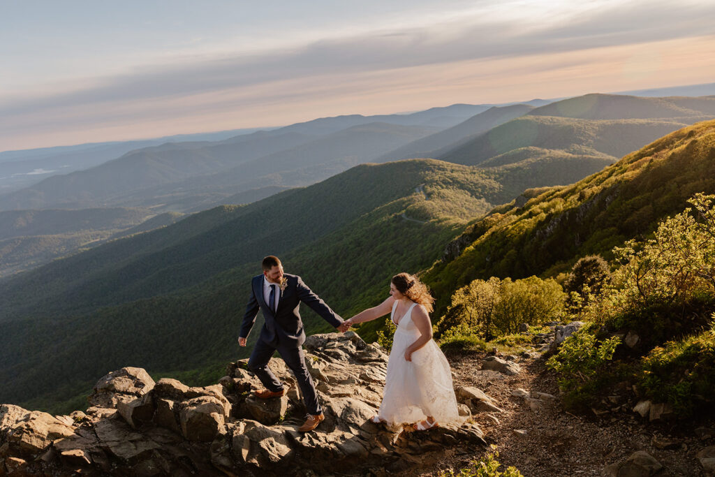 A groom leads his bride up a path in a dramatic photo in Shenandoah National Park as the sun rises