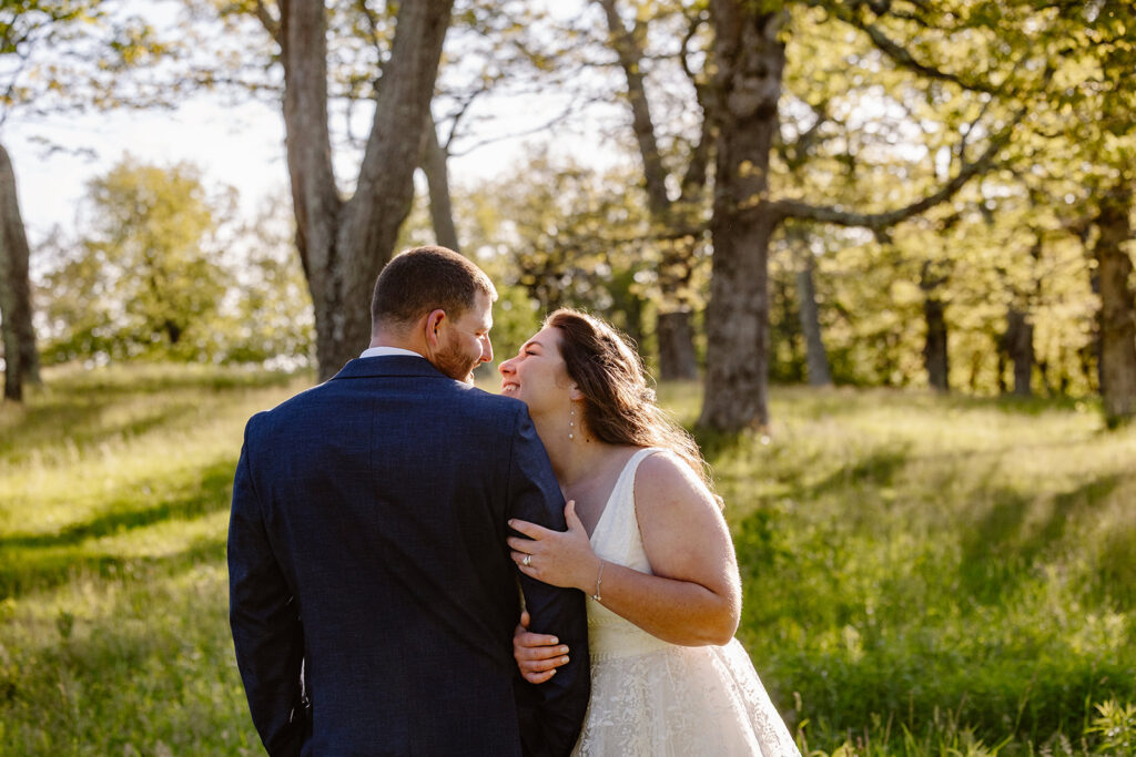 A bride snuggles into her grooms side smiling at him