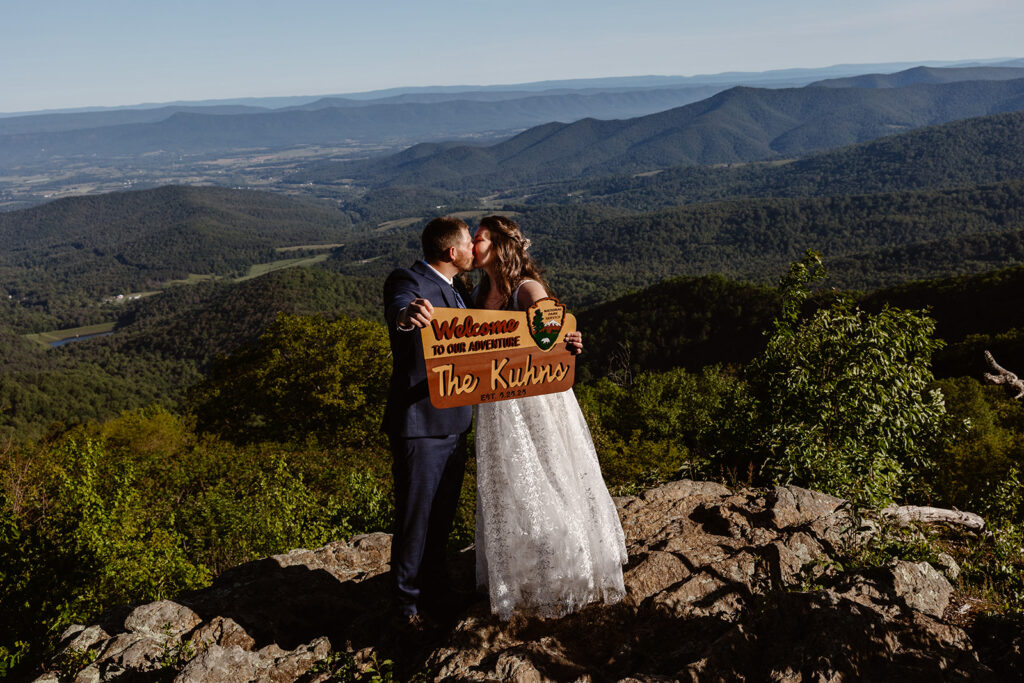 A bride and groom holding up  a sign that looks like a National Park sign during their elopement