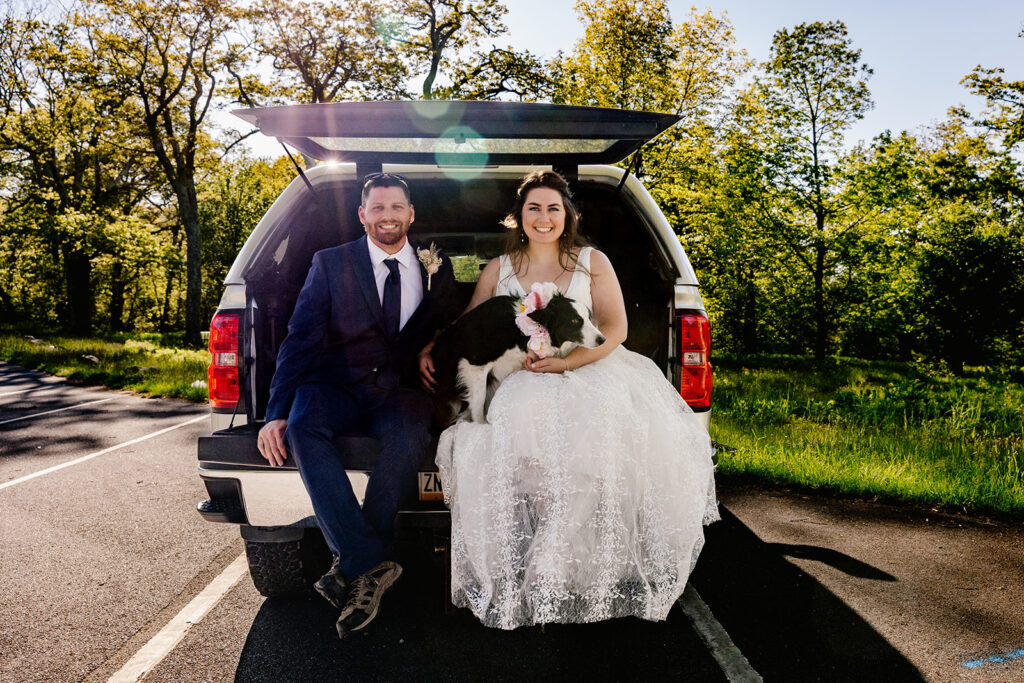 A bride, groom, and their dog Loop sitting in their camper truck on their wedding day