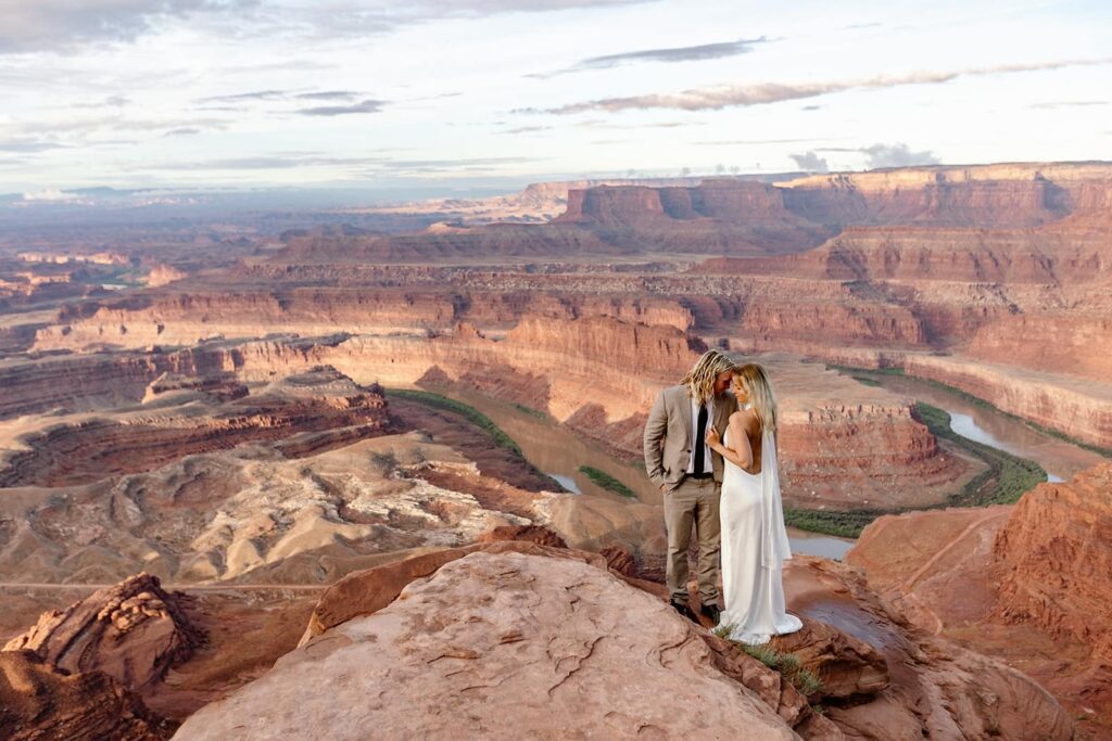A bride and groom stand at Dead Horse Point during their sunrise elopement