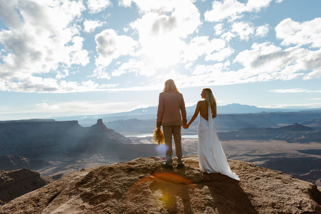 A bride and groom lookout at the canyon at Dead Horse Point as the sun rises.