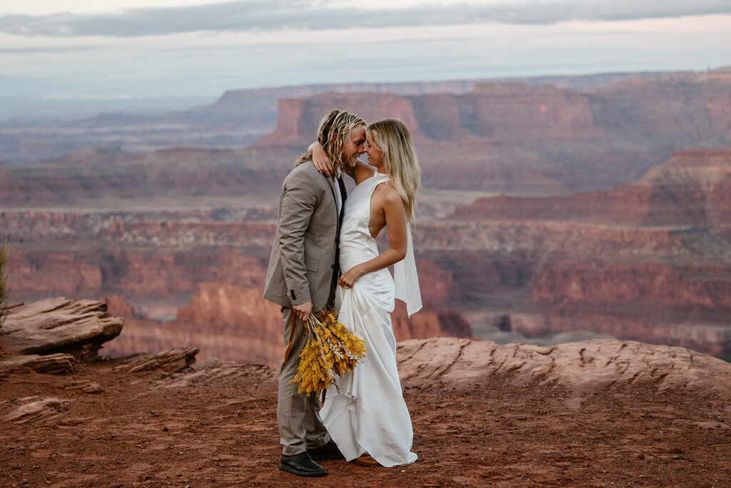 A bride and groom embrace at Dead Horse Point during their sunrise elopement