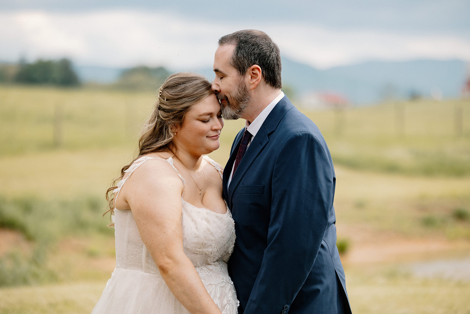 A groom kisses his bride on the forehead after the first look on their wedding day in Virginia