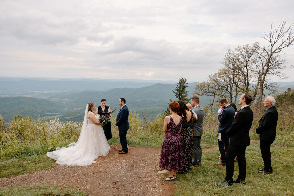 A bride and groom and their closest family gather for a micro wedding in Virginia. They are standing at an overlook during the ceremony.