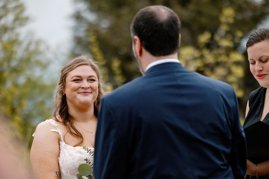 A bride s smiling while the groom says his vows