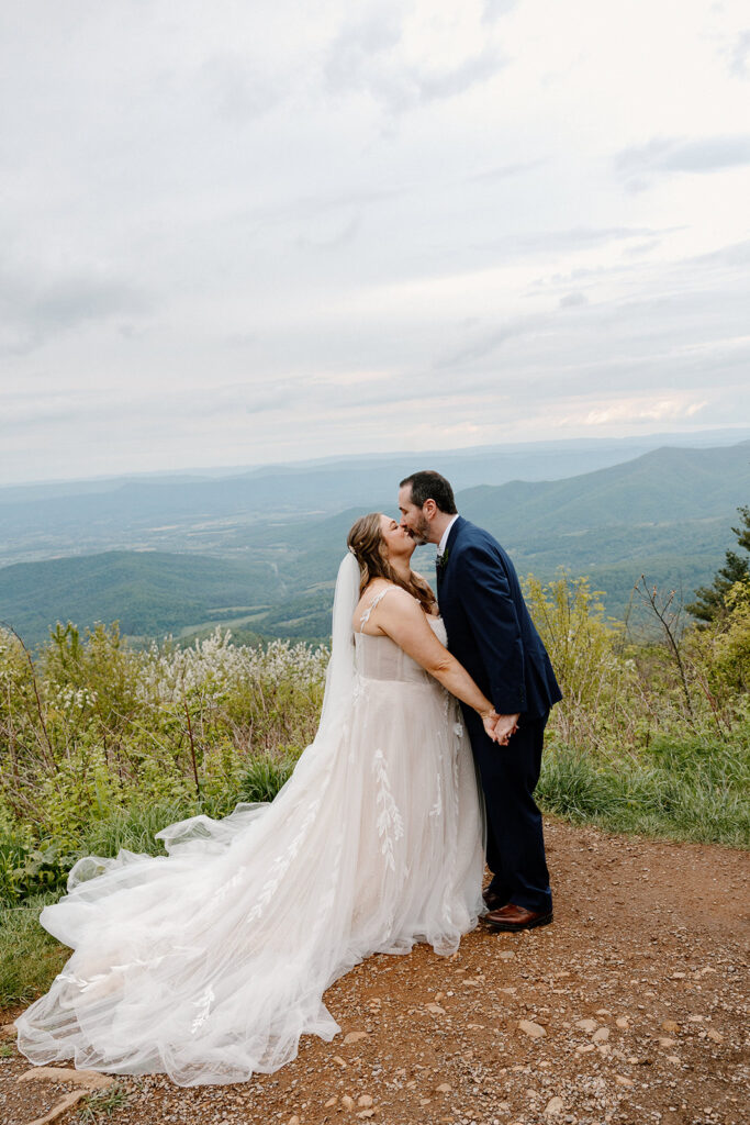 A bride and groom kiss for the first time at Jewell Hollow in Virginia. You can see the Blue ridge Mountains behind them
