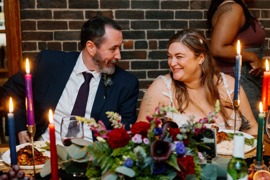 A bride and groom looking at each other smiling during their wedding reception. 