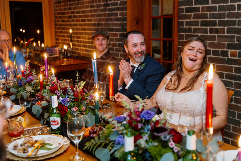 The bride and groom are laughing during a toast at their intimate reception. 