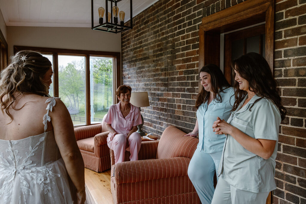A bride's sisters and mom look at the bride for the first time in her wedding dress. 