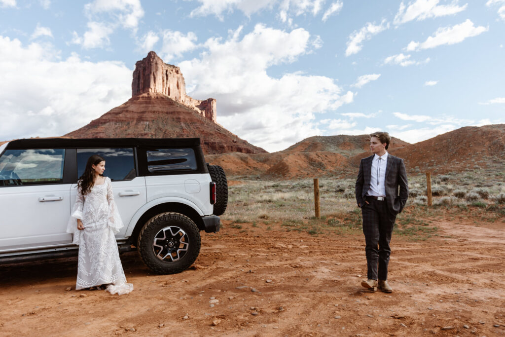 A bride looks at her groom for the first time before hiking to their ceremony spot. They are standing in front of Ida Gulch and their Ford Bronco.