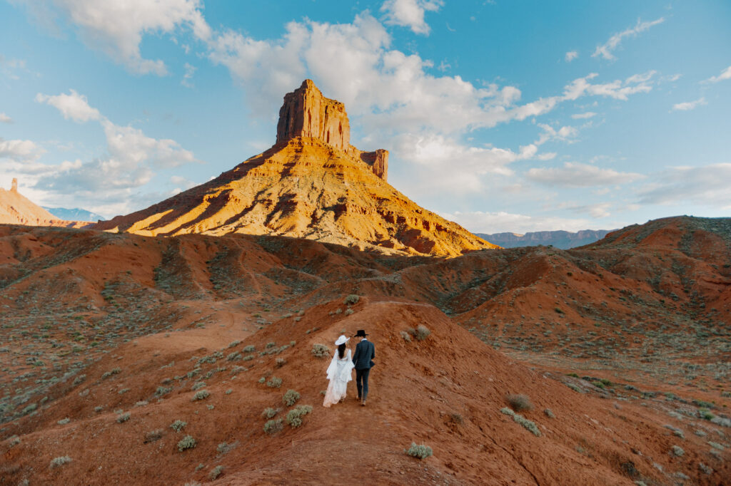 A bride and groom walking on the Ida Gulch Trail towards the ceremony site of their elopement