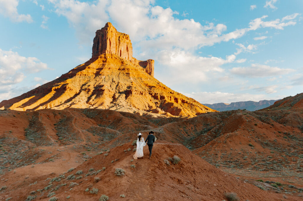 A bride and groom walking on the Ida Gulch Trail towards the ceremony site of their elopement
