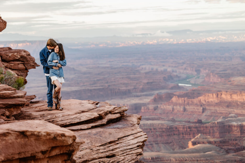 A couple stands on a rock at Dead Horse Point in Moab during their sunrise session of their elopement day