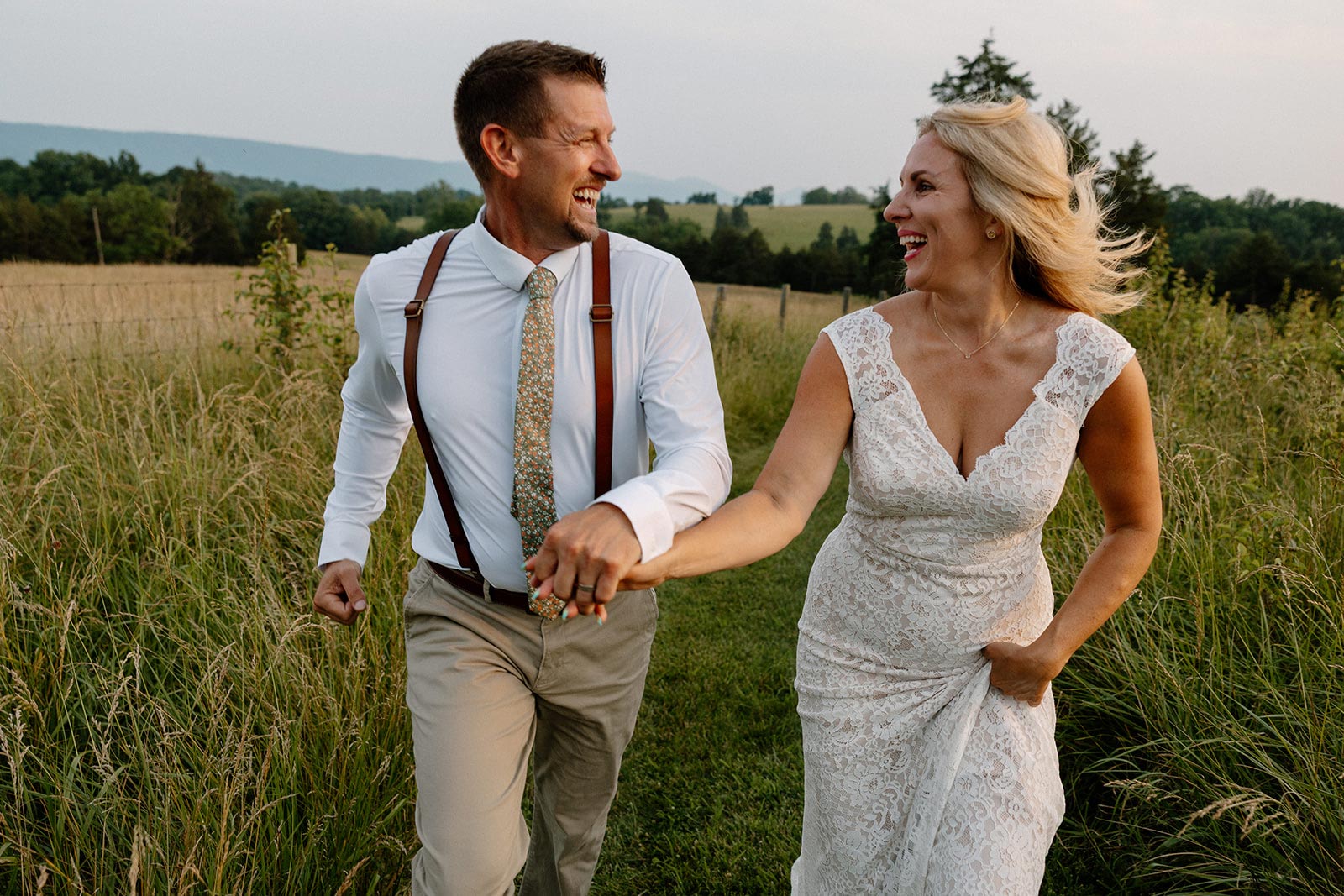 A couple holding hands laughing and running in a field in Virginia on their elopement day