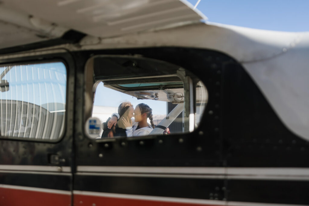 You can see a couple kissing through an airplane window, as they prepare to skydive on their elopement day. 