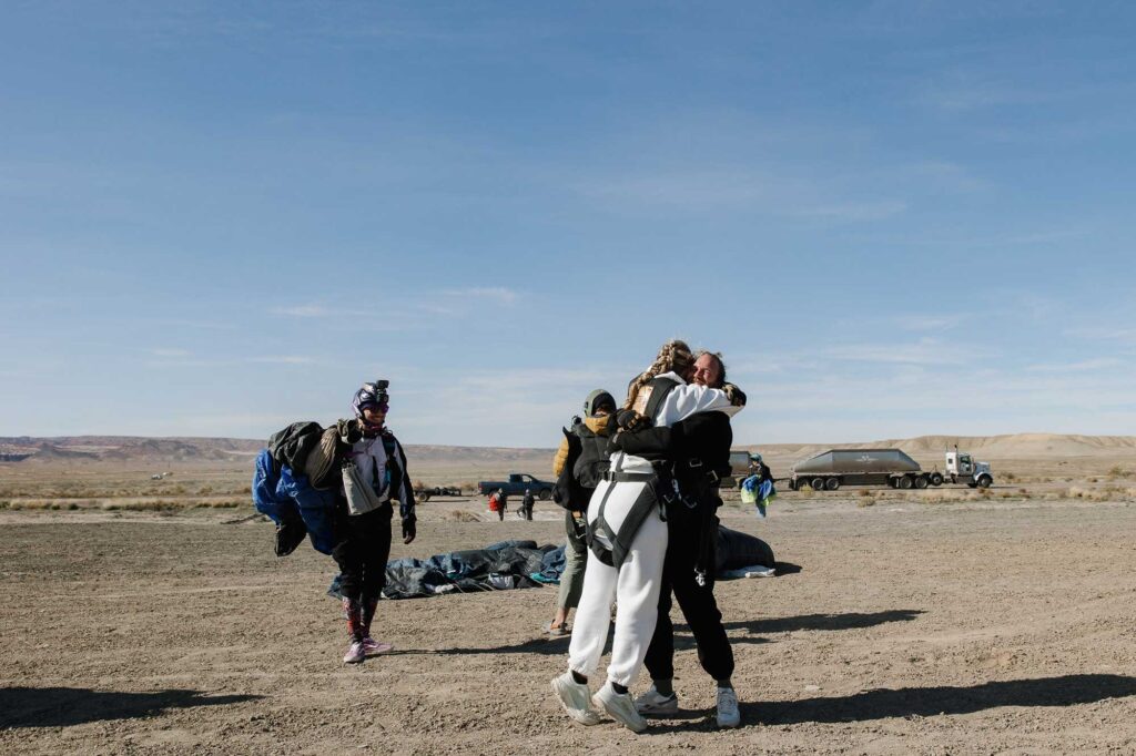 A bride and groom embrace after skydiving on their elopement day in Utah