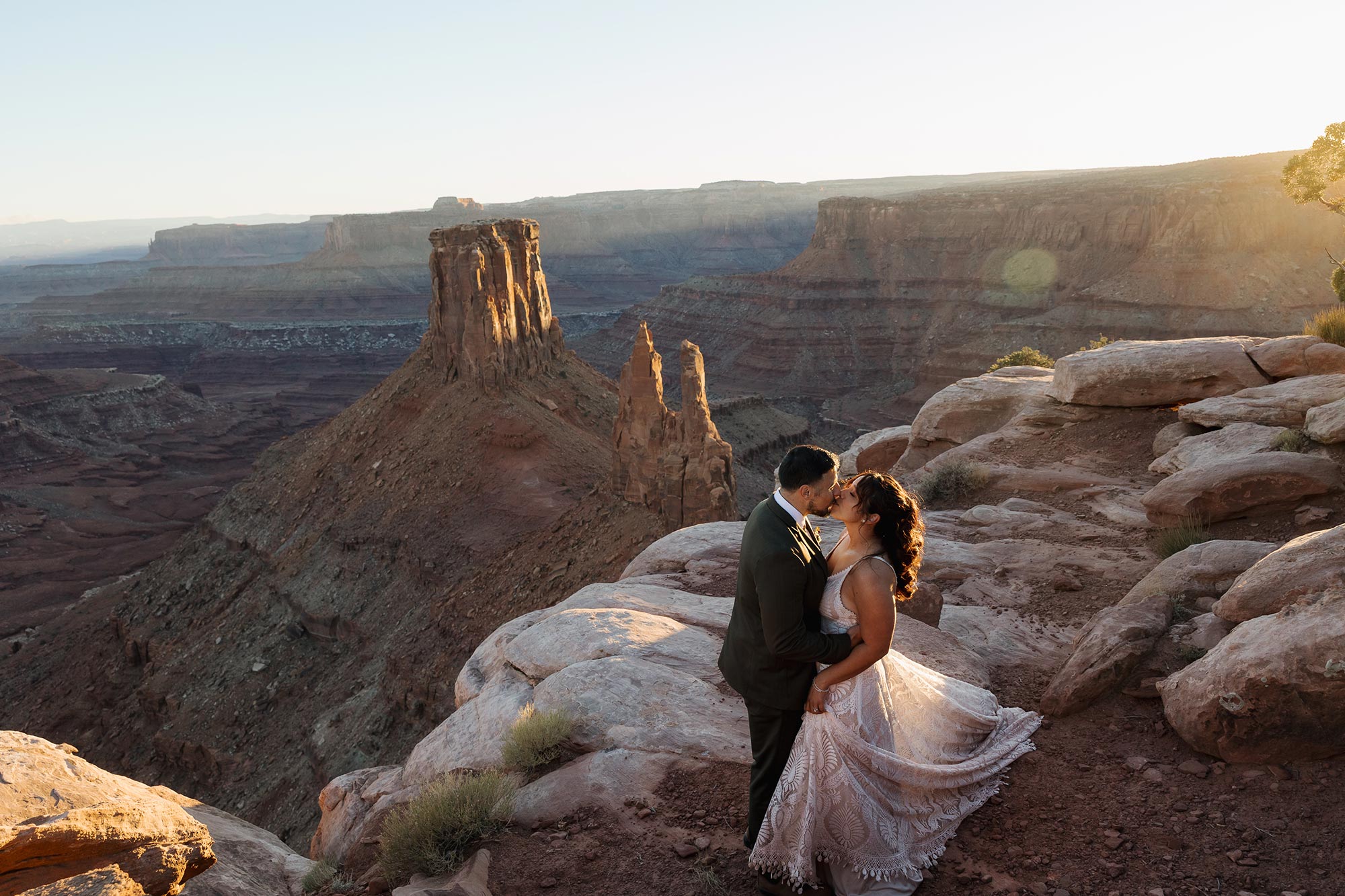 A couple kiss in front of Marlboro Point during their Moab elopement day as the sun starts to set.