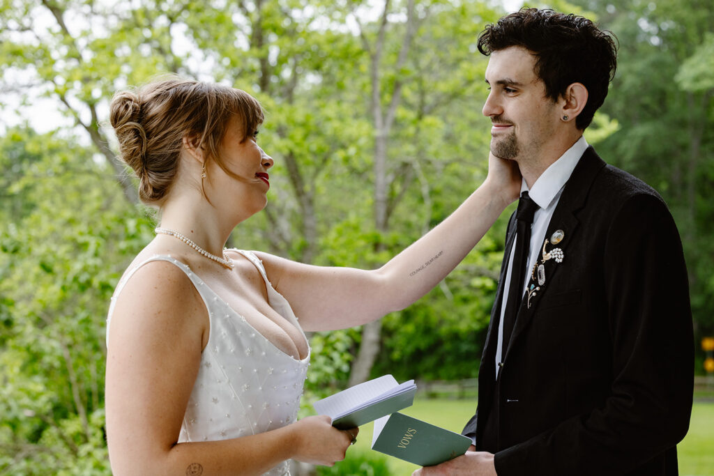 A bride gently touches her grooms cheek while exchanging vows outdoors in Pennsylvania