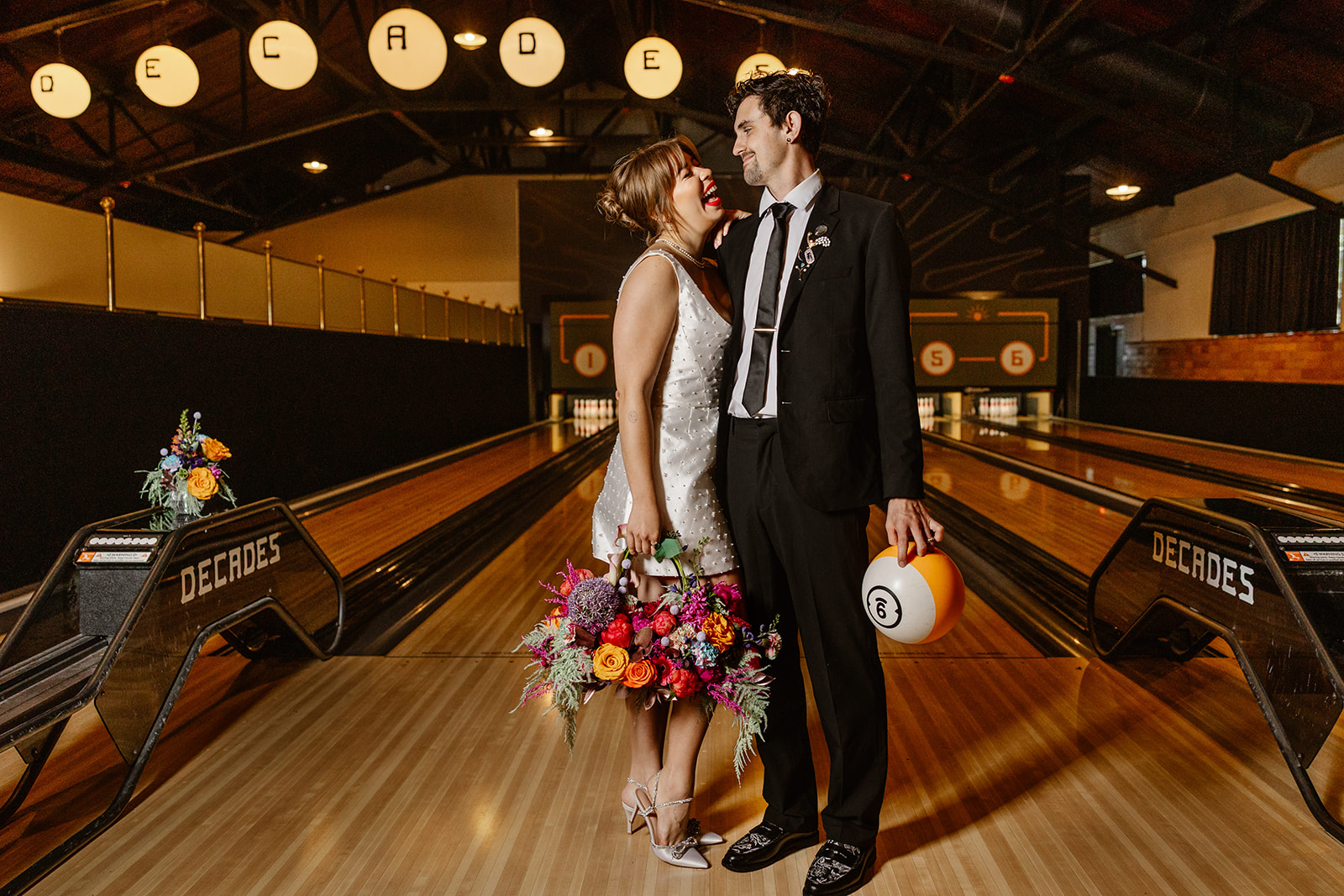 A couple stands in a bowling lane of a vintage arcade in lancaster during their elopement reception