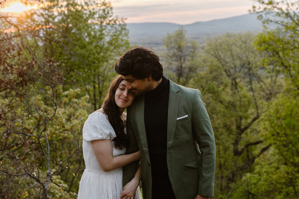 A birde holds her rooms arm, and snuggles in as they take a moment to enjoy the sunrising and the fact they are officially married