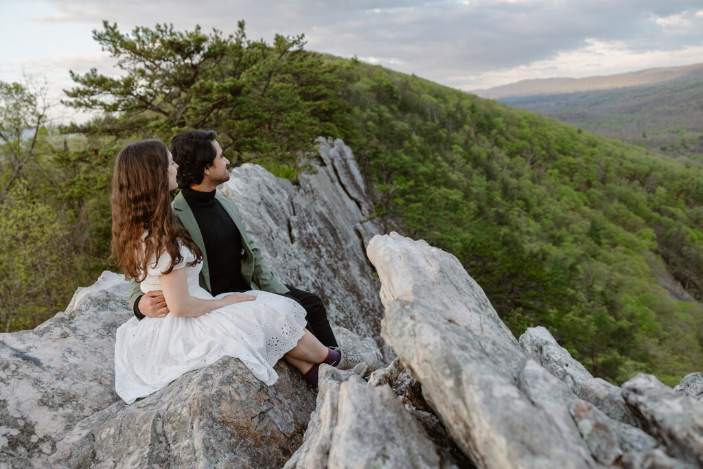 A bride and groom sit on rocks admiring the view on their elopement day