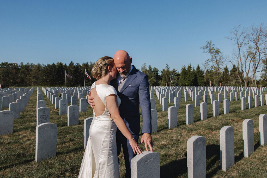 A bride and groom take a moment to pay tribute to the grooms grandfather at Indiantown Gap Military Cemetary.