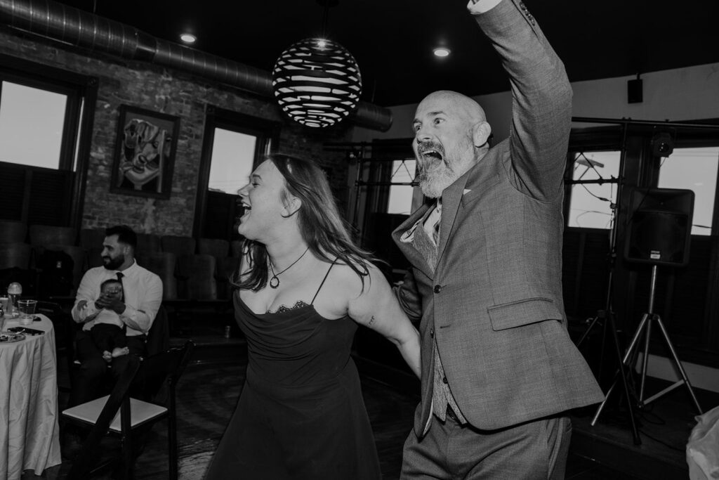 A groom and his daughter hype up the room during the grooms wedding reception.