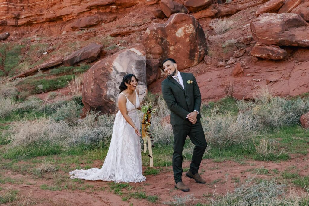 A groom turns around to see his bride during their first look. They are surrounded by red cliffs in Moab