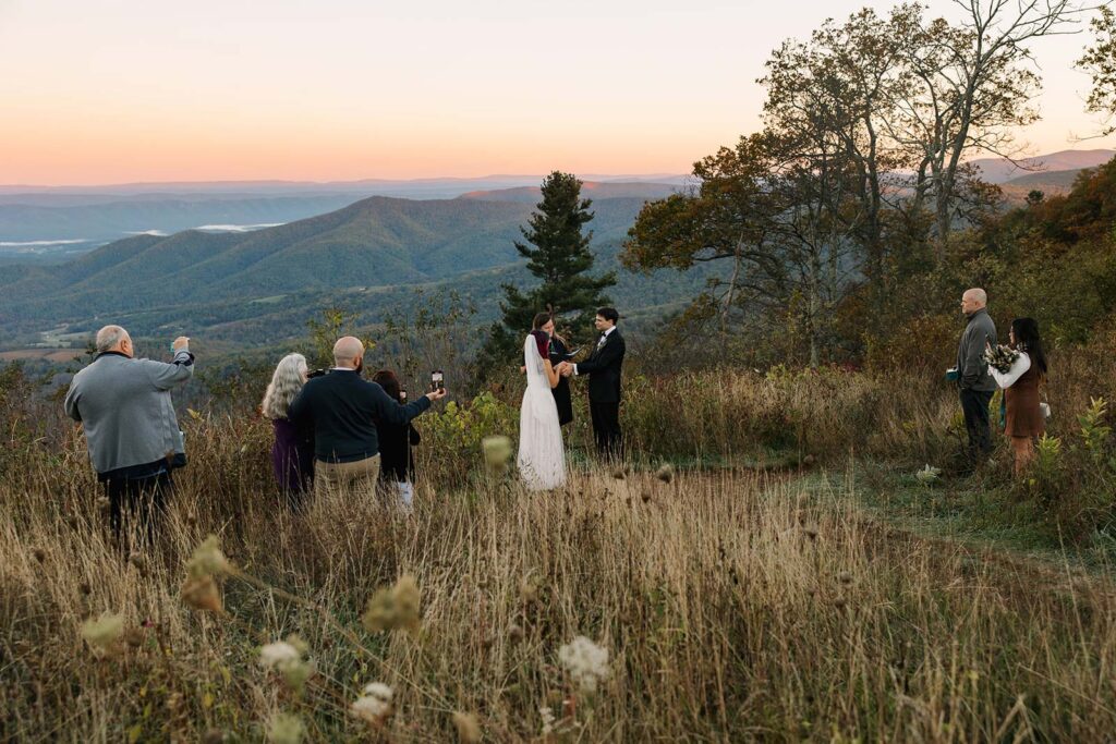 A bride and groom stand in front of their immediate family during their sunrise ceremony at Jewell Hollow Overlook
