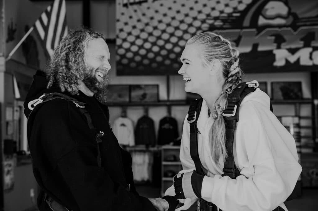 A bride and groom laughing off the nerves of getting ready to go skydiving in Moab