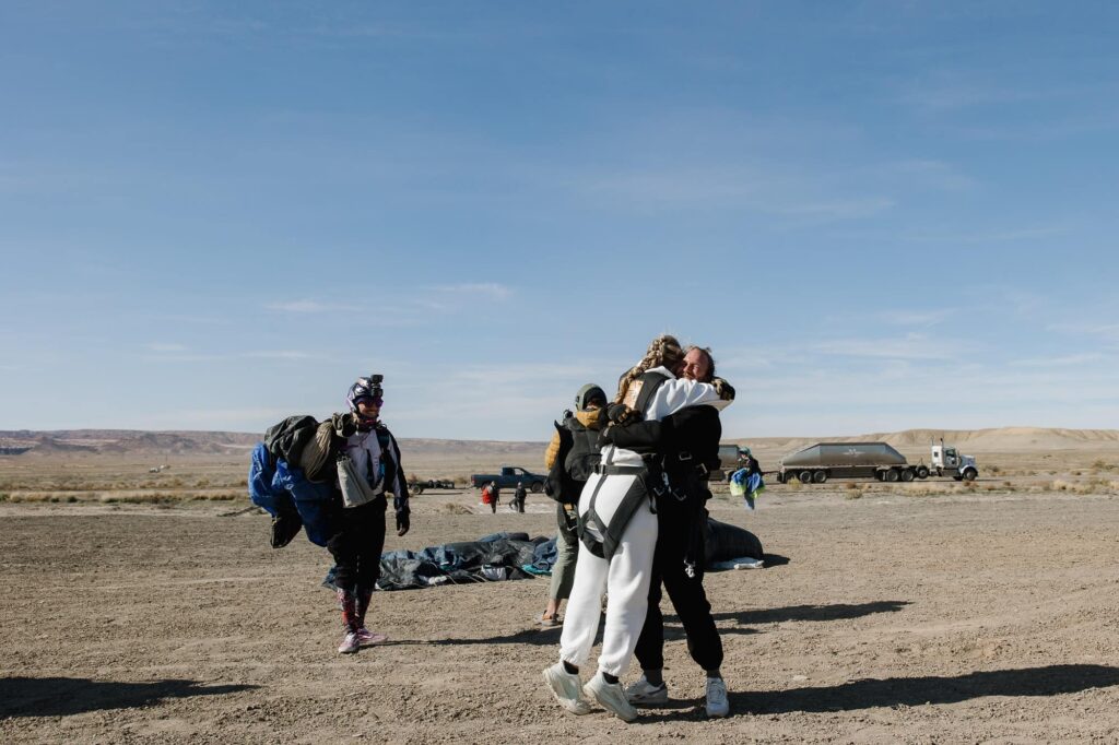 A groom picks up his bride once they see each other after skydiving for the first time on their elopement day
