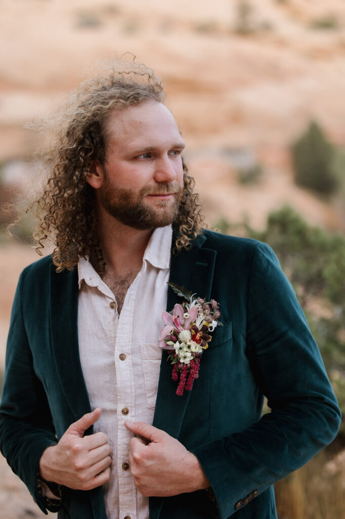 A groom with long curly hair in a green velvet suit on his elopement day