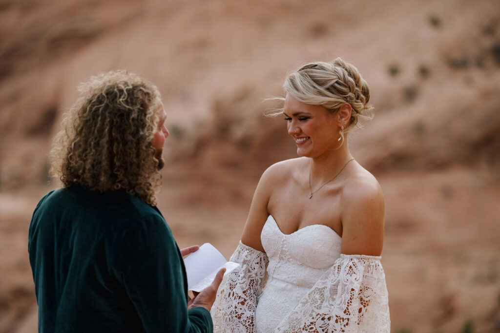 A bride laughs at the vows her groom wrote to her. He is reading them during their elopement ceremony,