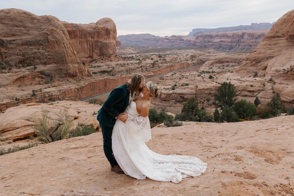 A bride and groom dip kiss at the end of their elopement ceremony in the Moab desert