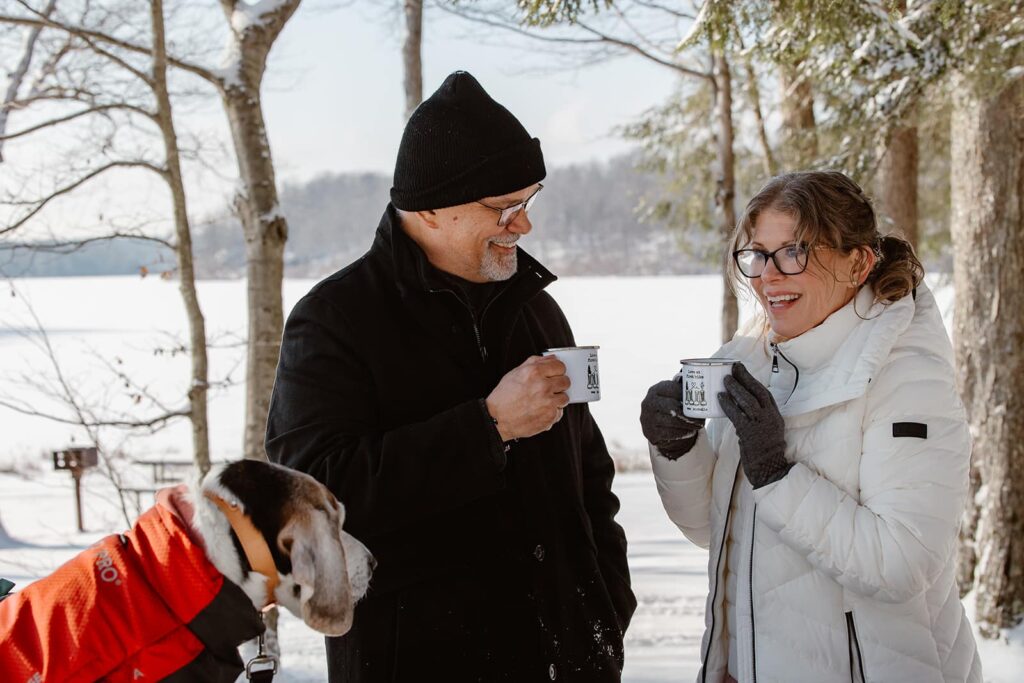 A bride and groom take a moment during their snowy elopement day for a picnic lunch and some warm apple cider.