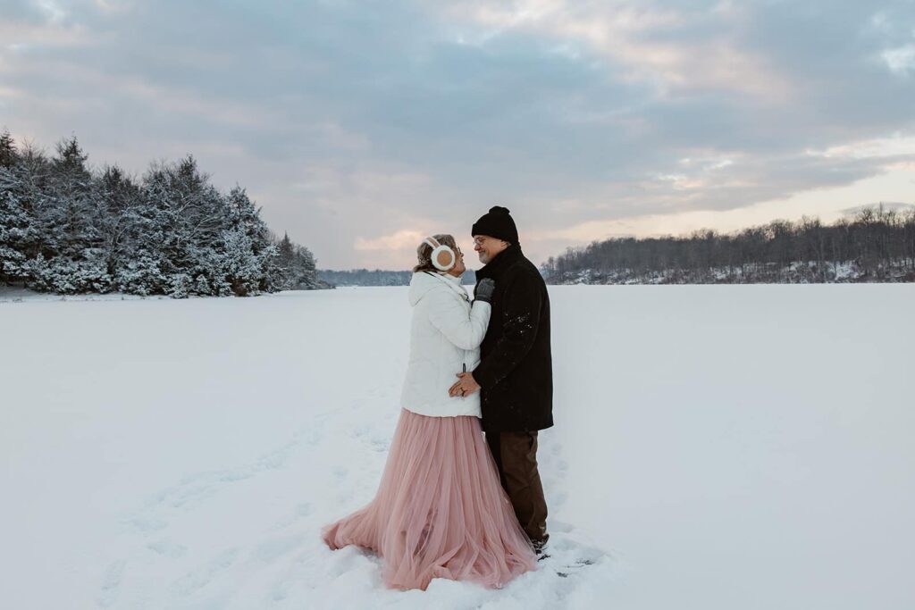 A bride and groom take a walk on the ice of Lake Jean as the sunsets on their wedding day