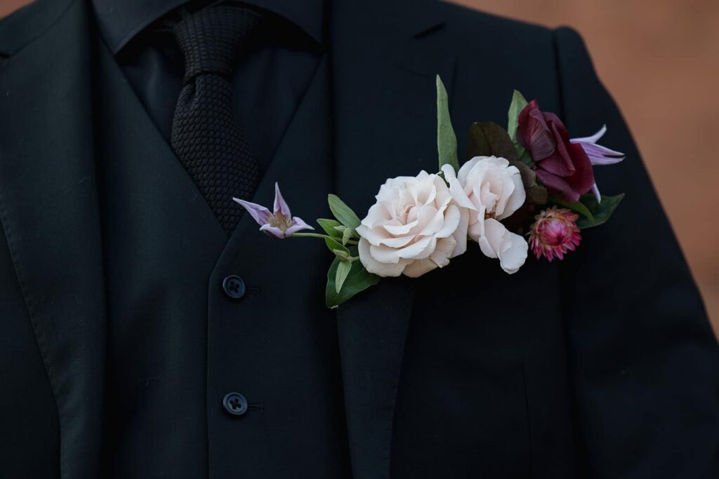 A closeup of a grooms boutonniere against his black suit. 