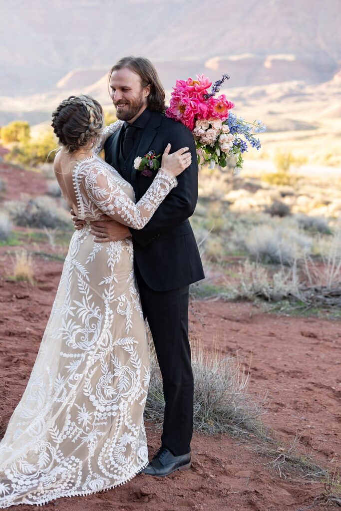 A bride and groom face each other smiling and embracing during their Moab Elopement.