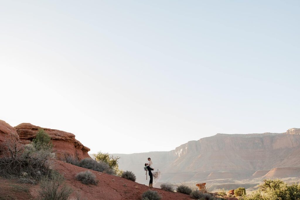 A groom lifts up his bride in the Castle Valley area as the sunsets on their elopement day. 