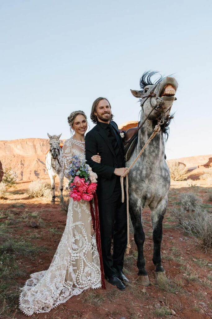 A horse bucks and shows its teeth as a couple pets it. The couple deciding to include horse  into their adventure elopement in Moab