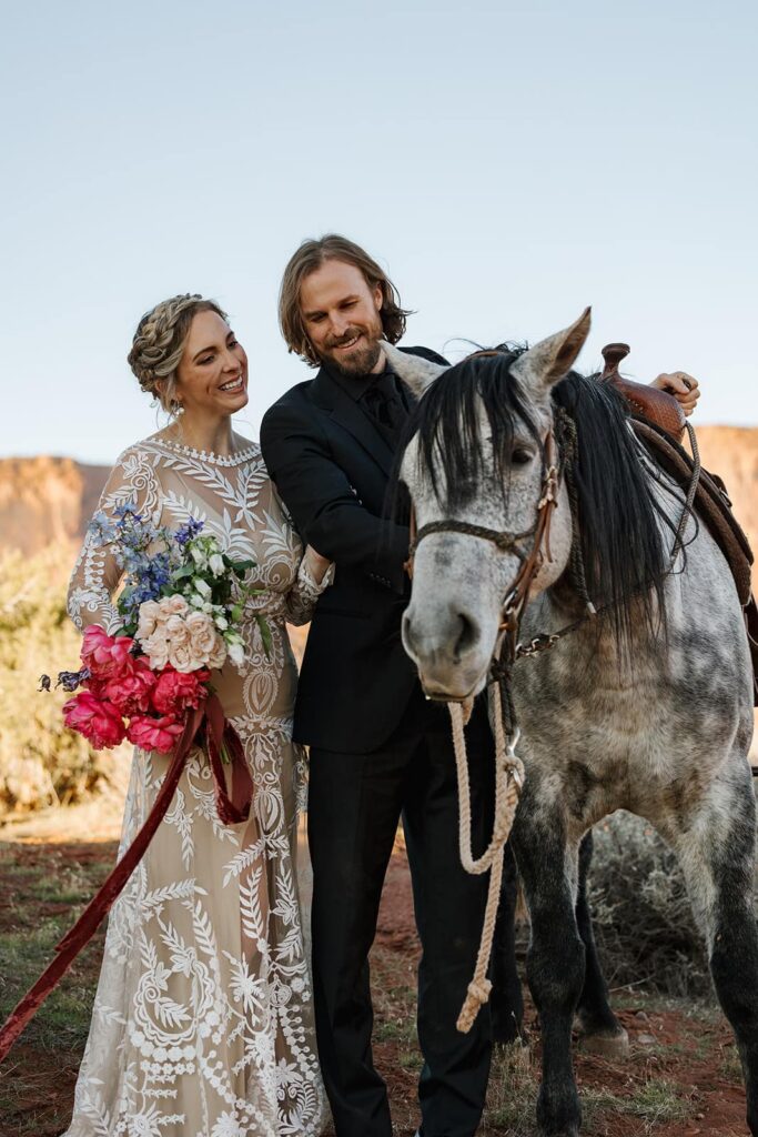 A bride and groom pet a horse, and look at it lovingly during their adventure elopement in Utah.