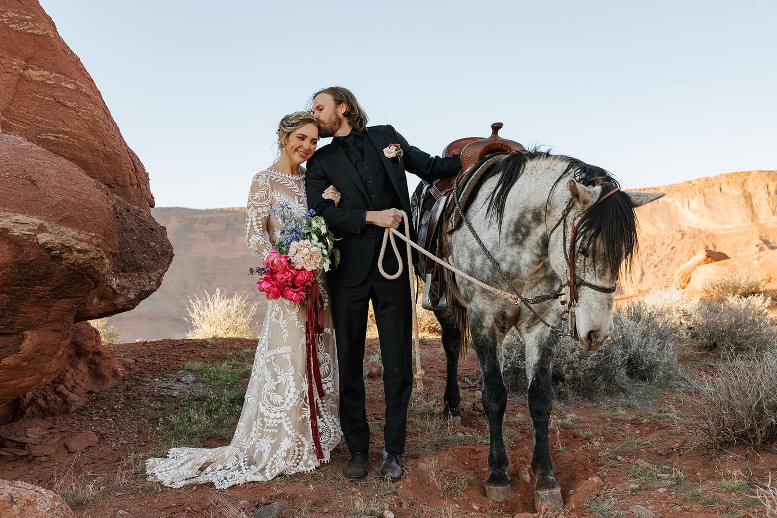 A bride and groom stand with a horse during their adventure elopement