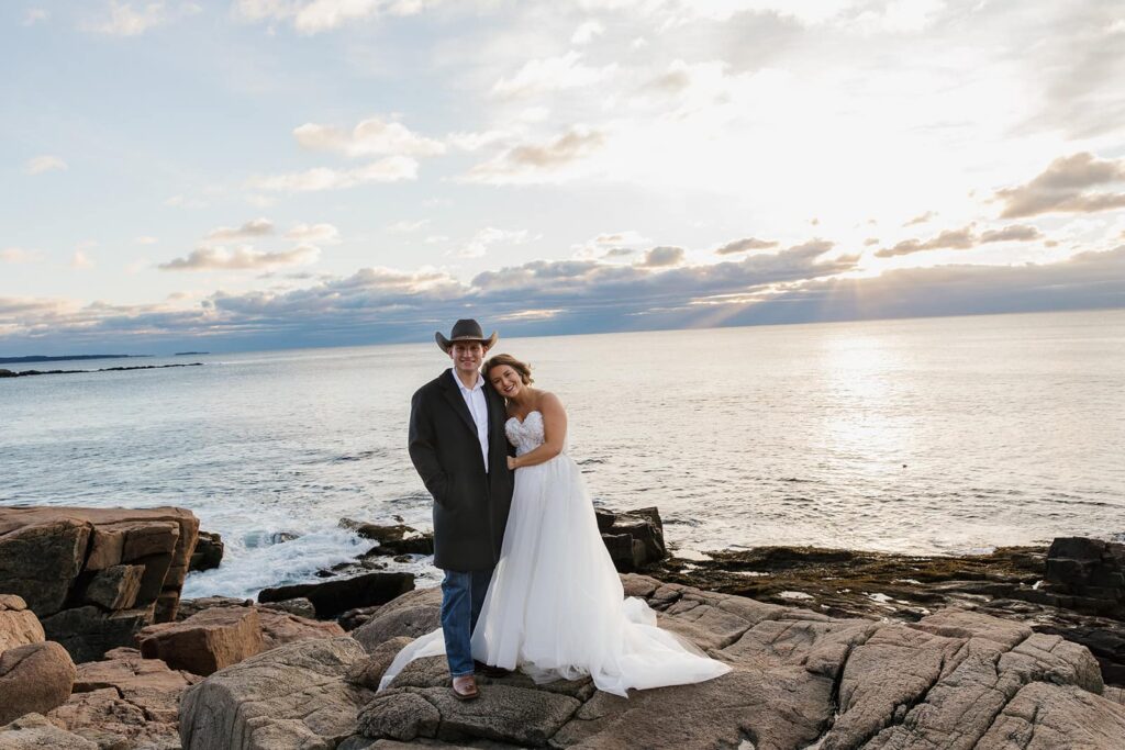 A bride and groom stand at Otter Cliffs at Acadia National Park during their sunrise elopement in Maine