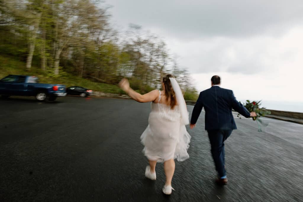 A bride and groom run towards their car as it starts pouring on their wedding day.