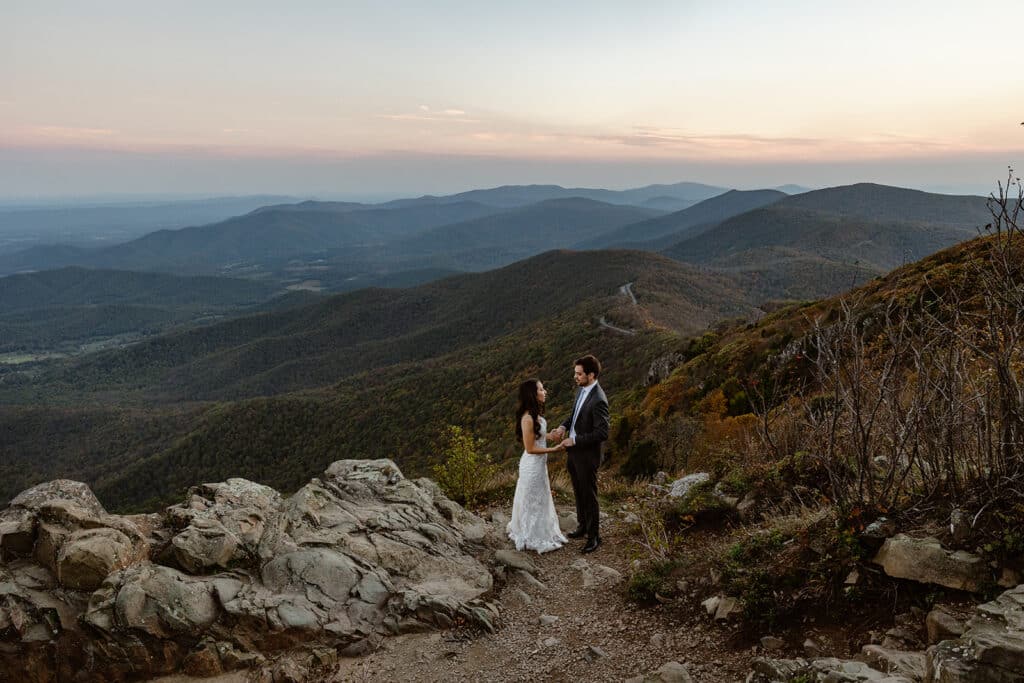 A bride and groom stand holding hands during their sunrise elopement at Shenandoah Elopement