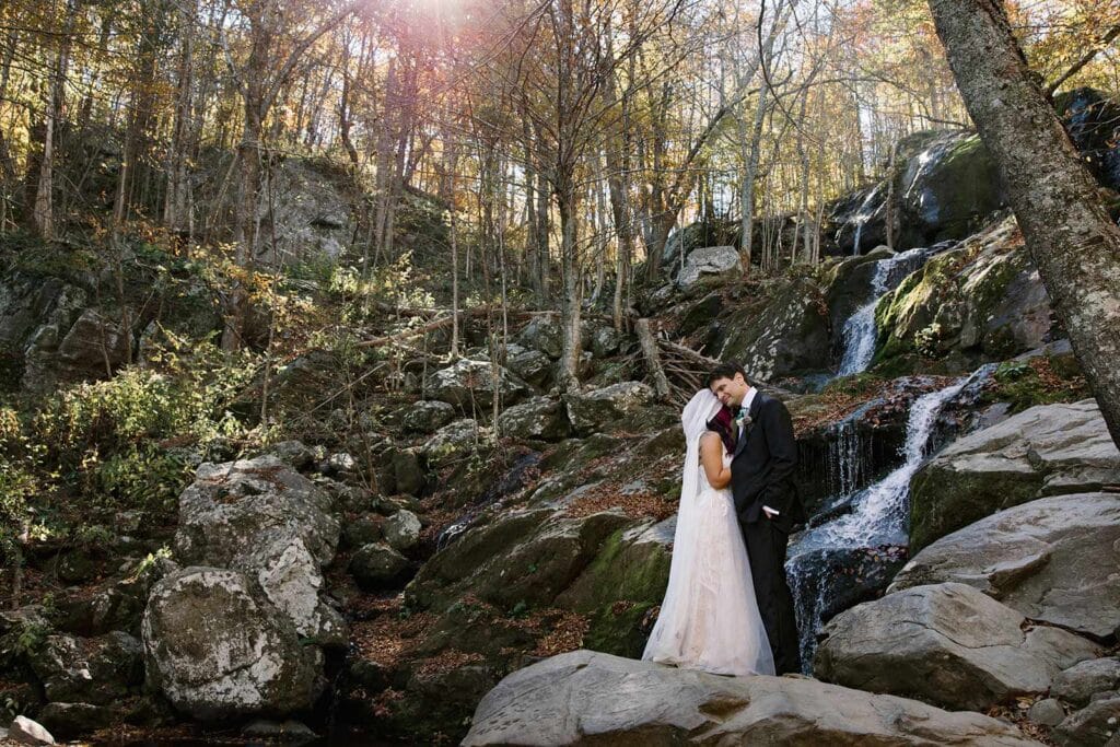 A bride and groom stand in front of Dark Hollow Falls during their Shenandoah Elopement