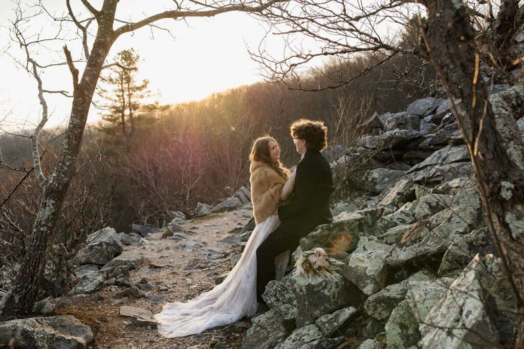 A couple leans on a rock pile at Black Rock Summit as the sun rises during their sunrise elopement