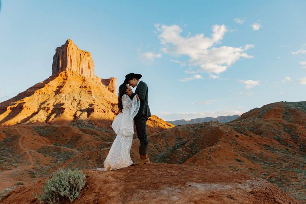 A bride and groom, almost kissing stand in front of a desert landscape during their elopement. What to pack for your desert elopement.